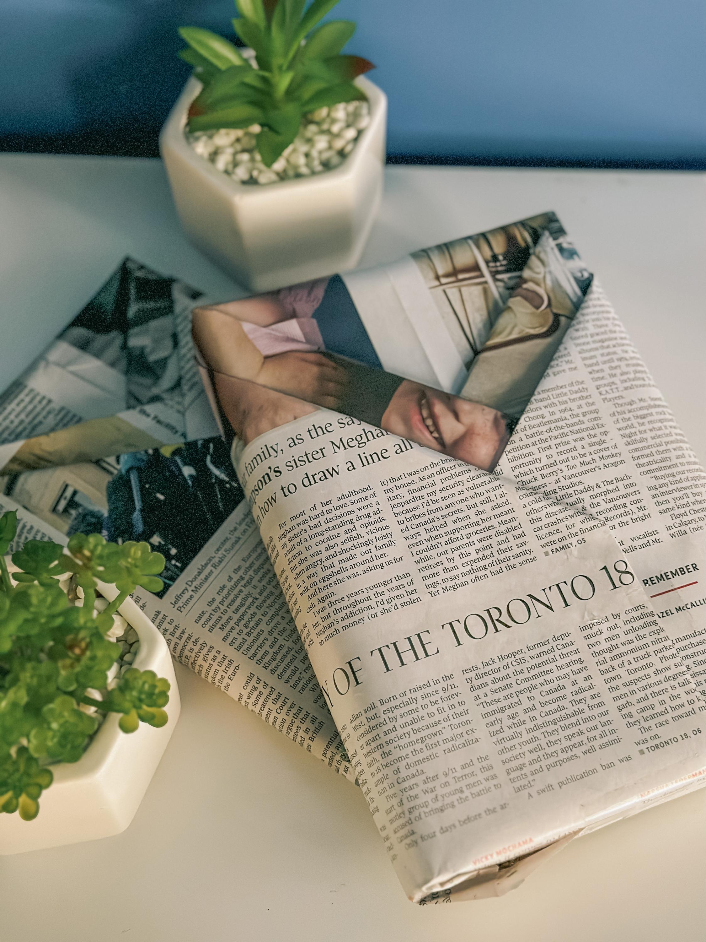 Newspaper folded as books on the table and next to small pots of plants next to them