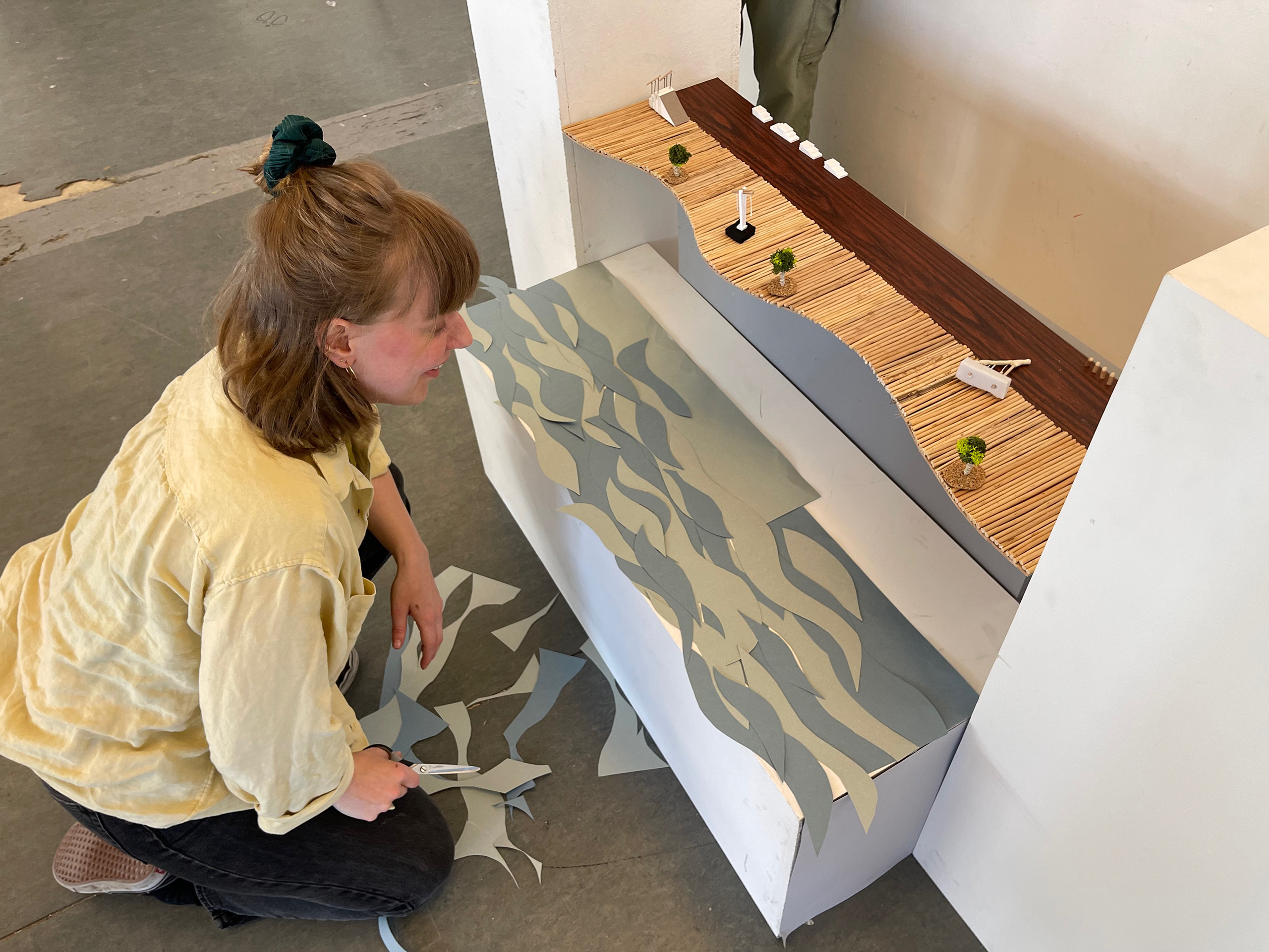 Student works on an art pieve with several scraps of paper