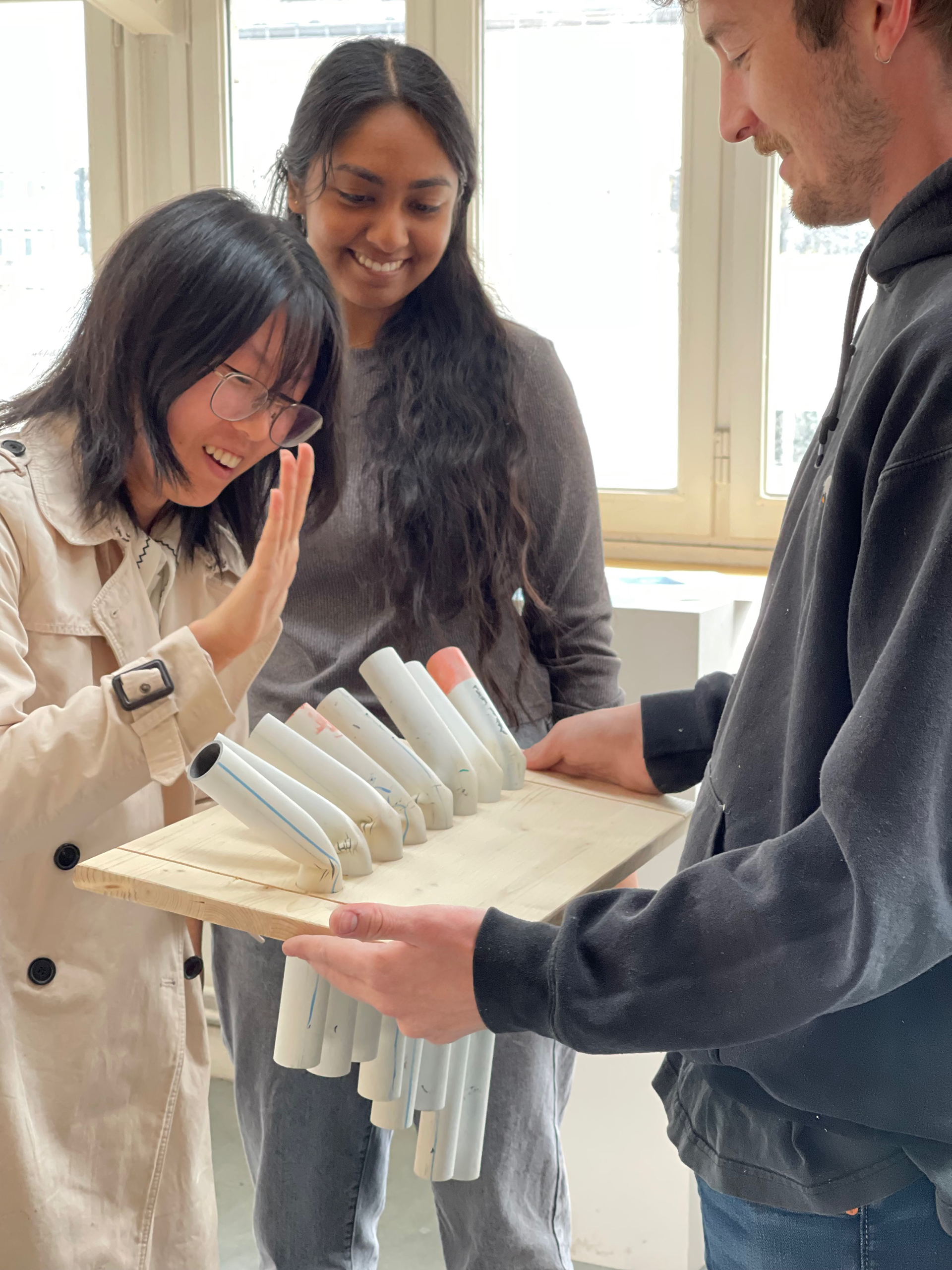 A student holds a project as two other students interact with it