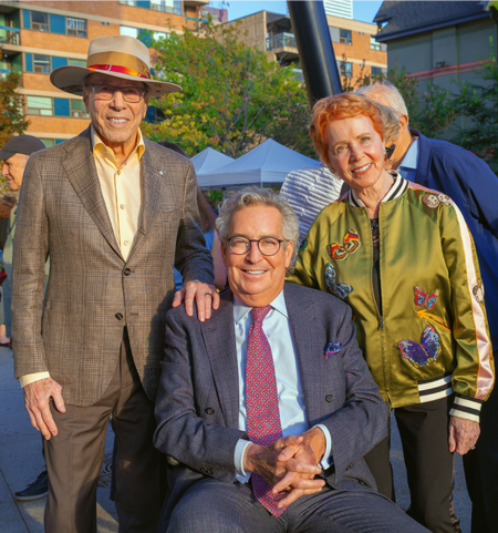 Photo of three guests attending park celebration outside while smiling.
