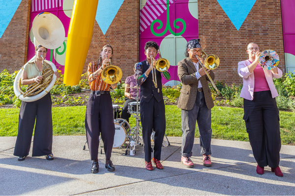 Photograph of live band playing brass instruments outside 