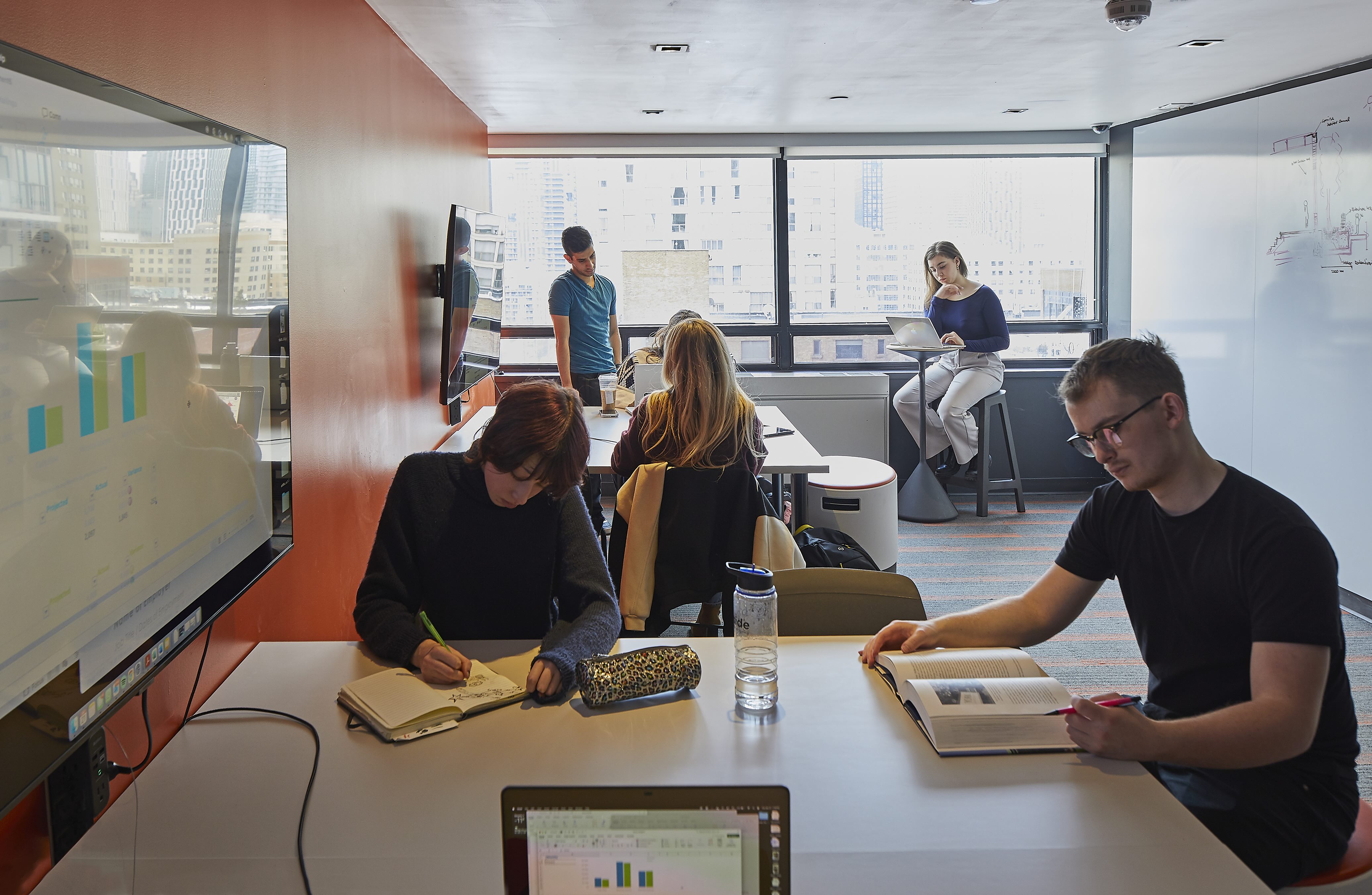 A room with whiteboards and students at desks working
