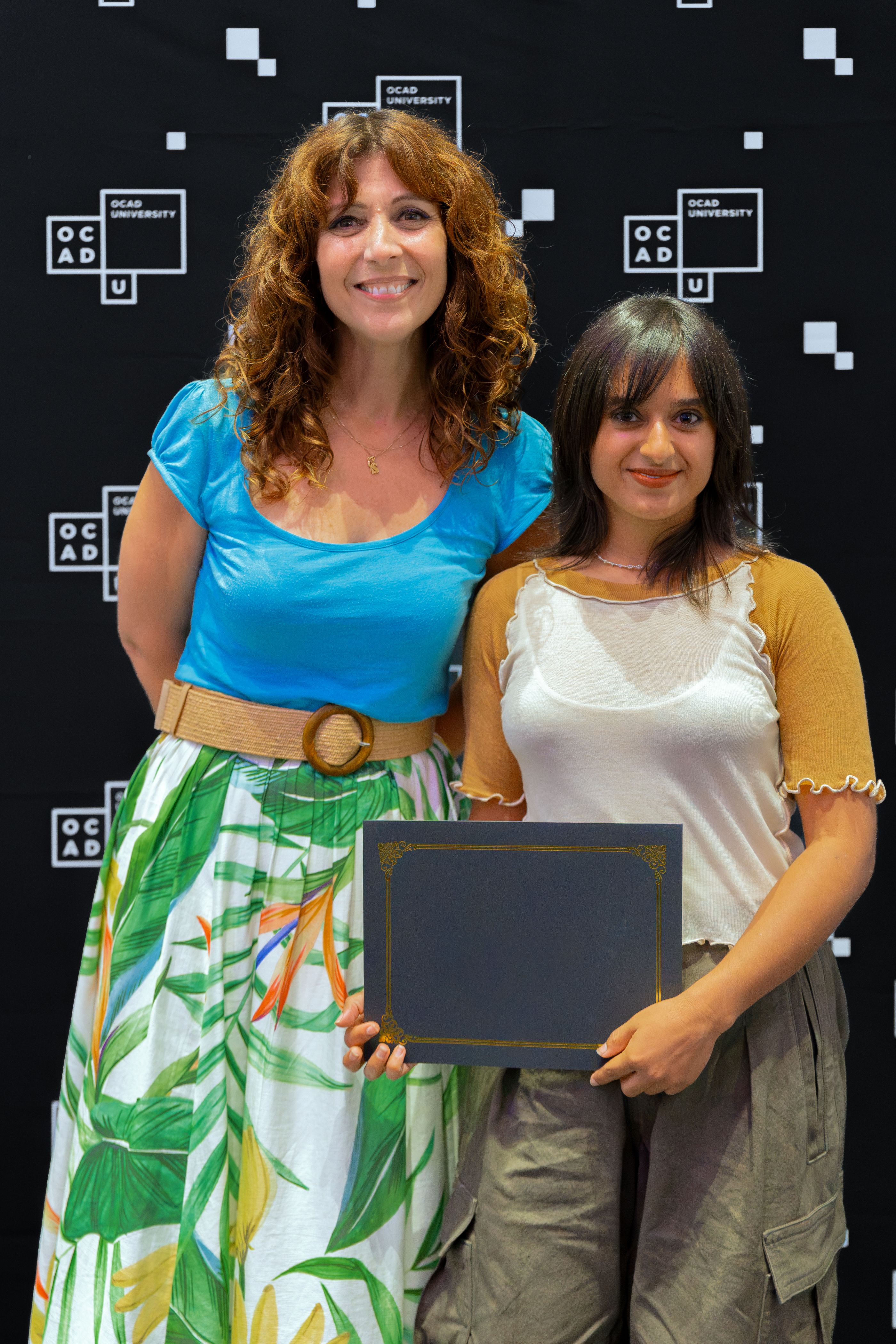 Left to right: Dr. Gabriele wearing blue top and white and green skirt with Alisha Ali, wearing white and yellow top with khaki pants. 