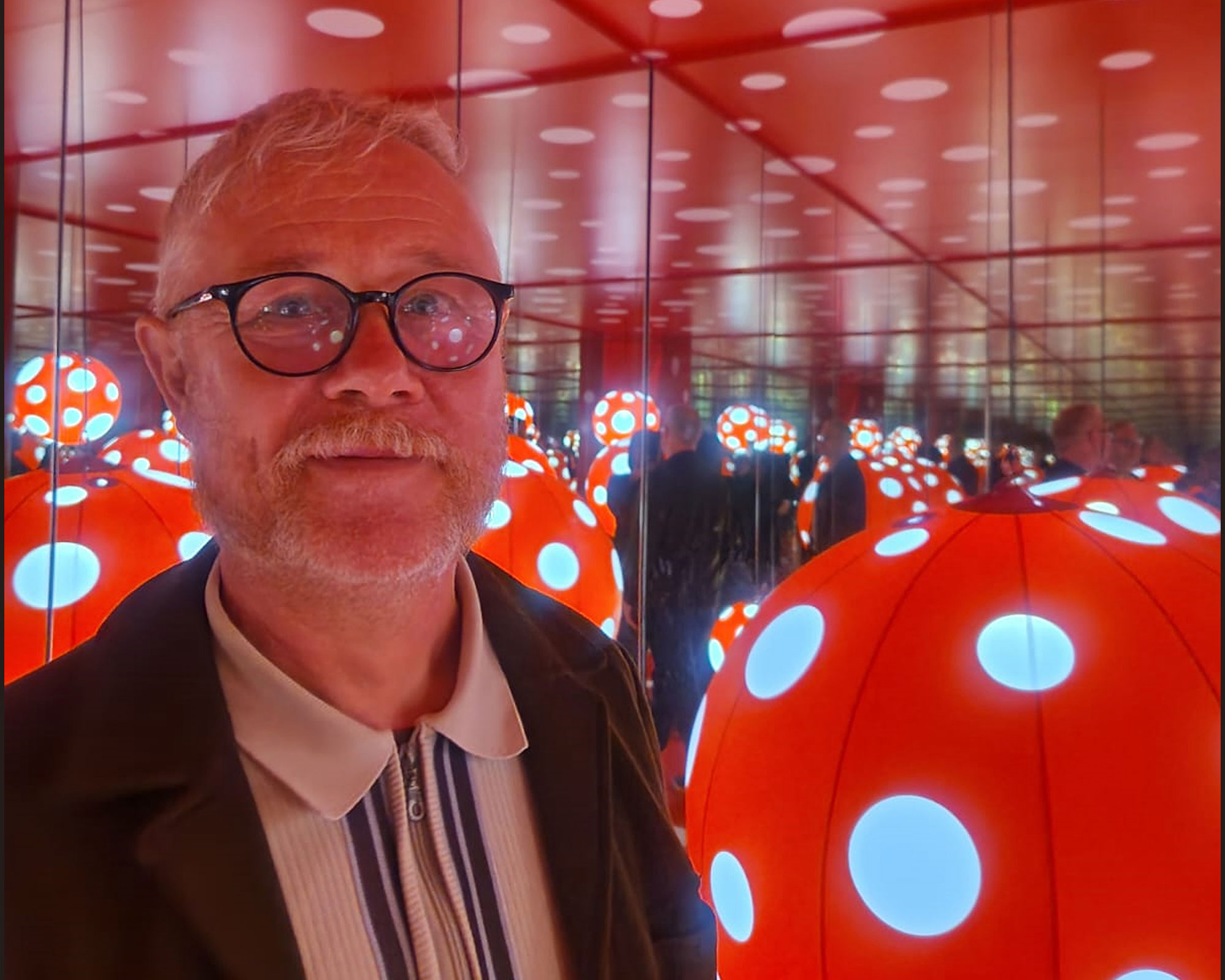 Paul Murnaghan - man wearing glasses in a room with round balls with blue dots