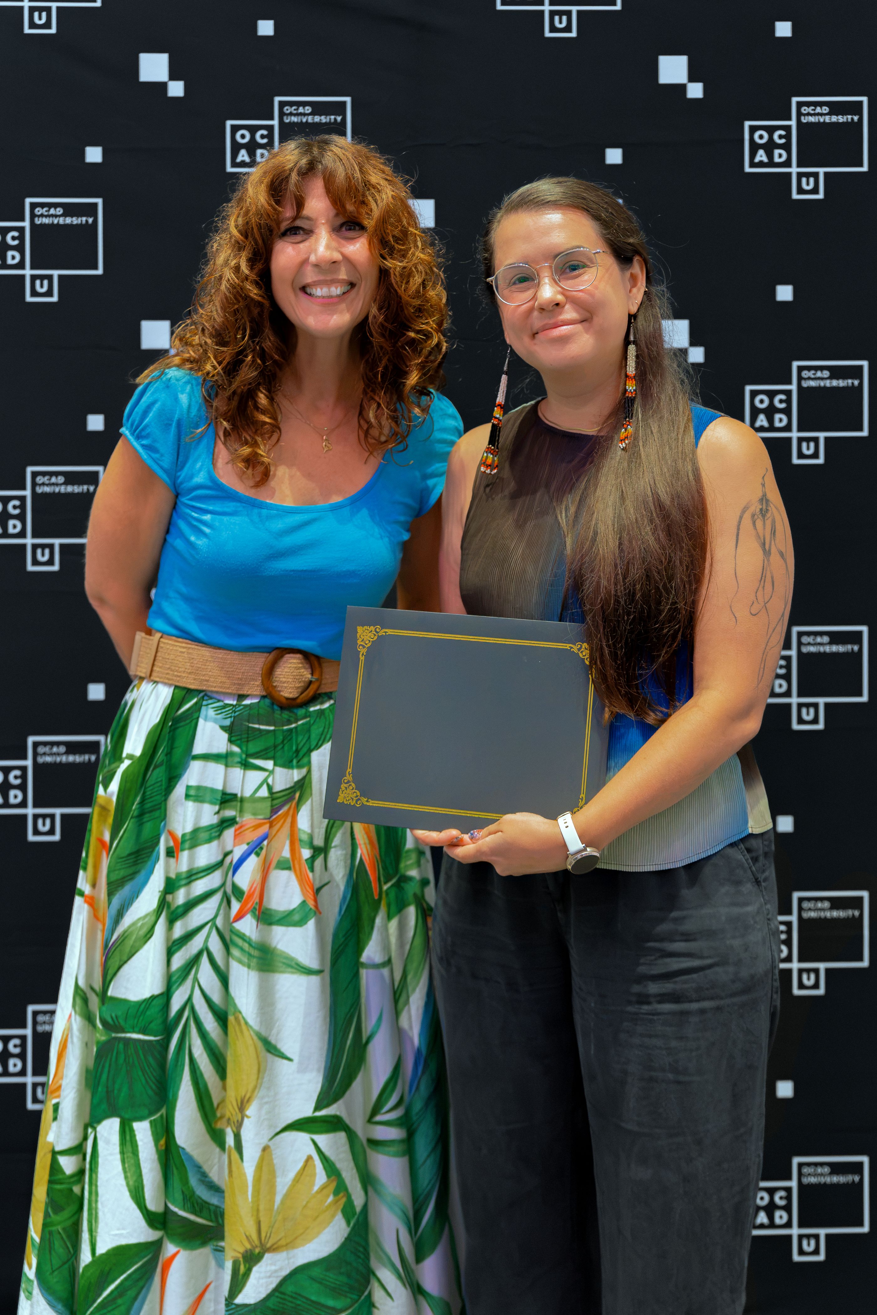 Left to right: Dr. Gabriele wearing a blue top and green and white skirt with SJ Okemow, wearing blue and black top and black pants.