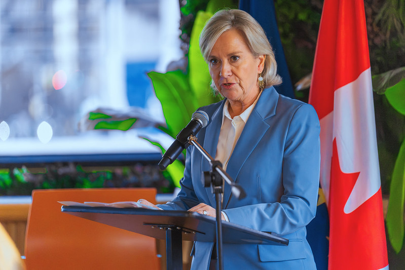 Geneviève Tuts, Ambassador of the EU to Canada at podium, wearing a blue jacket and white shirt. 