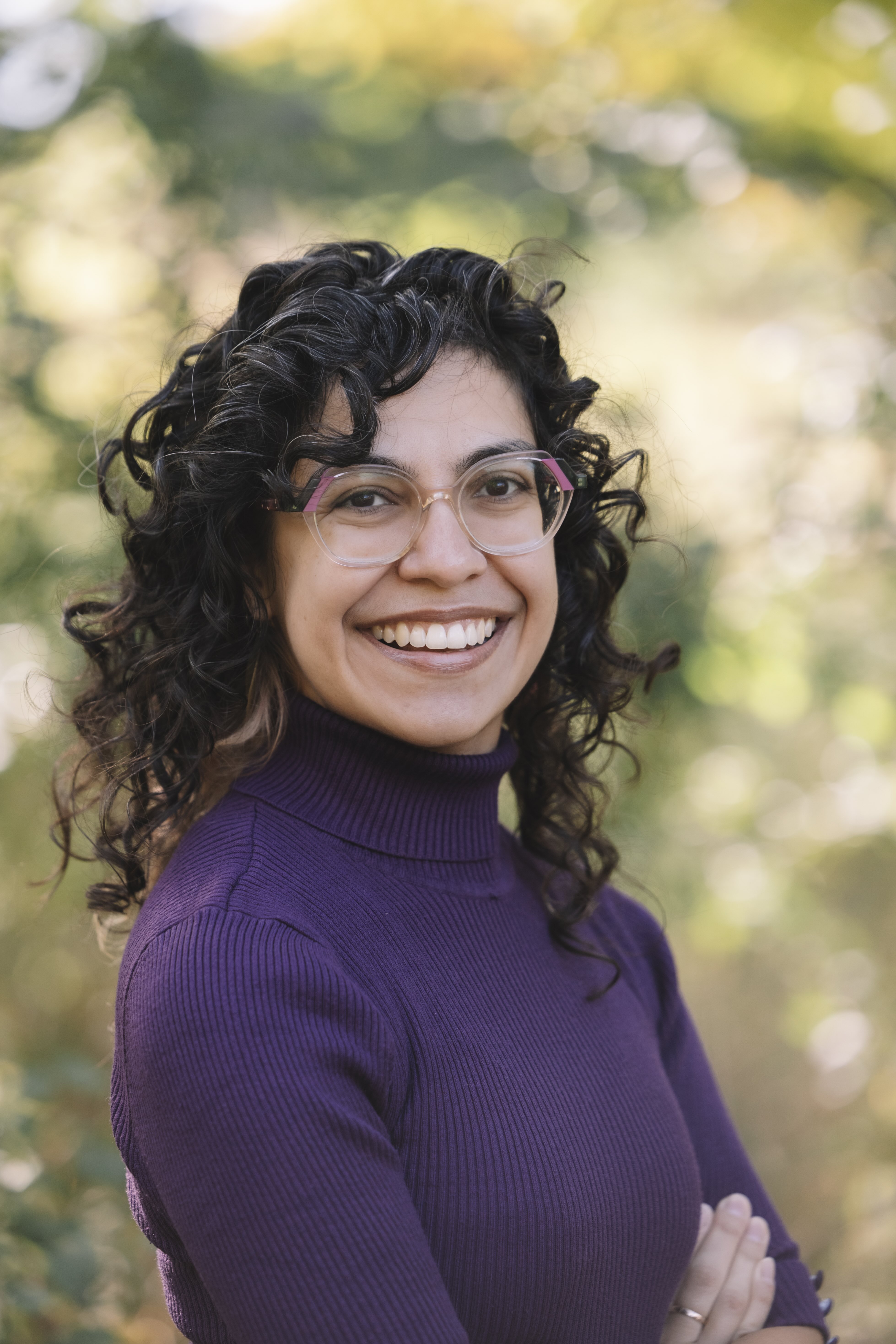 Woman with curly hair wearing glasses and a purple shirt