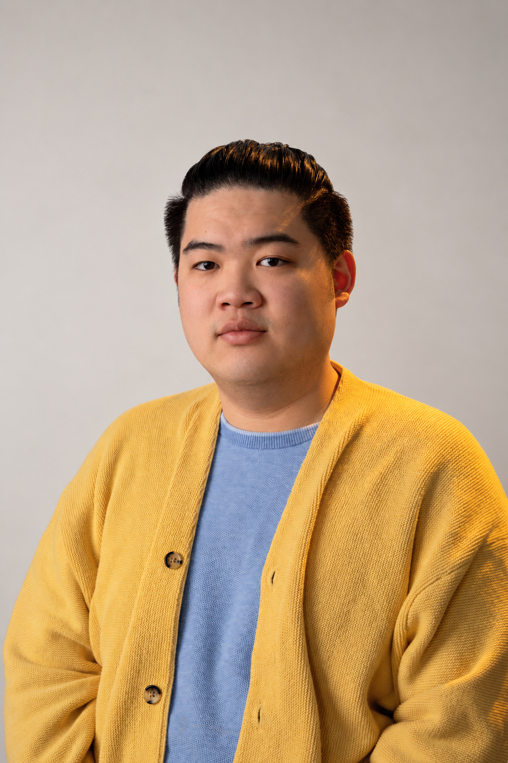 Image of young man wearing gold/yellow sweater with blue shirt