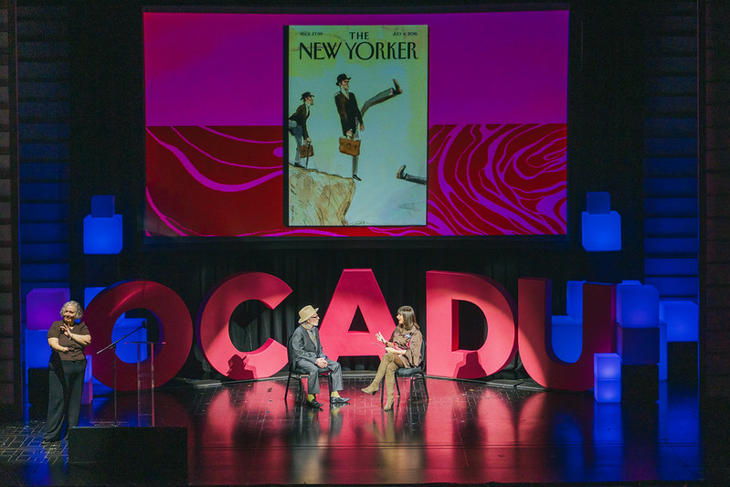 Barry Blitt on stage with Jeanne Beker with OCAD U in the background and New Yorker illustration on the screen