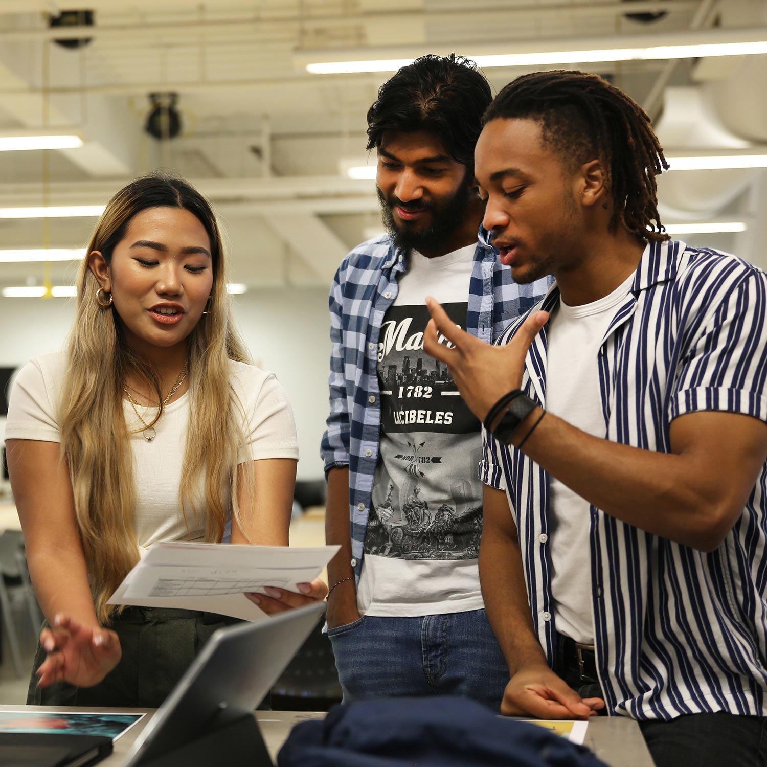 Three students gathered in a circle discussing something.