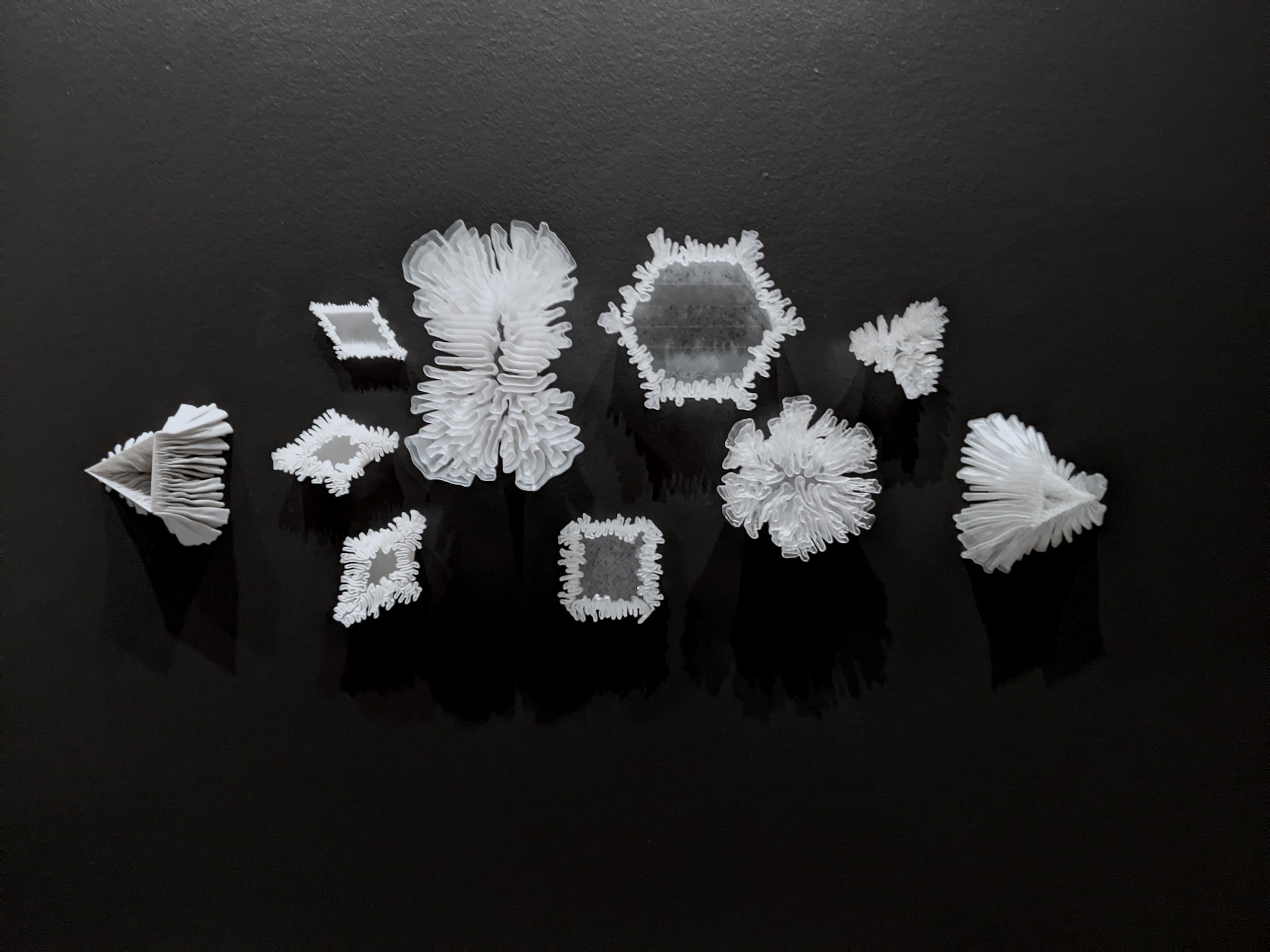A collection of 3D printed objects in white on a black background.