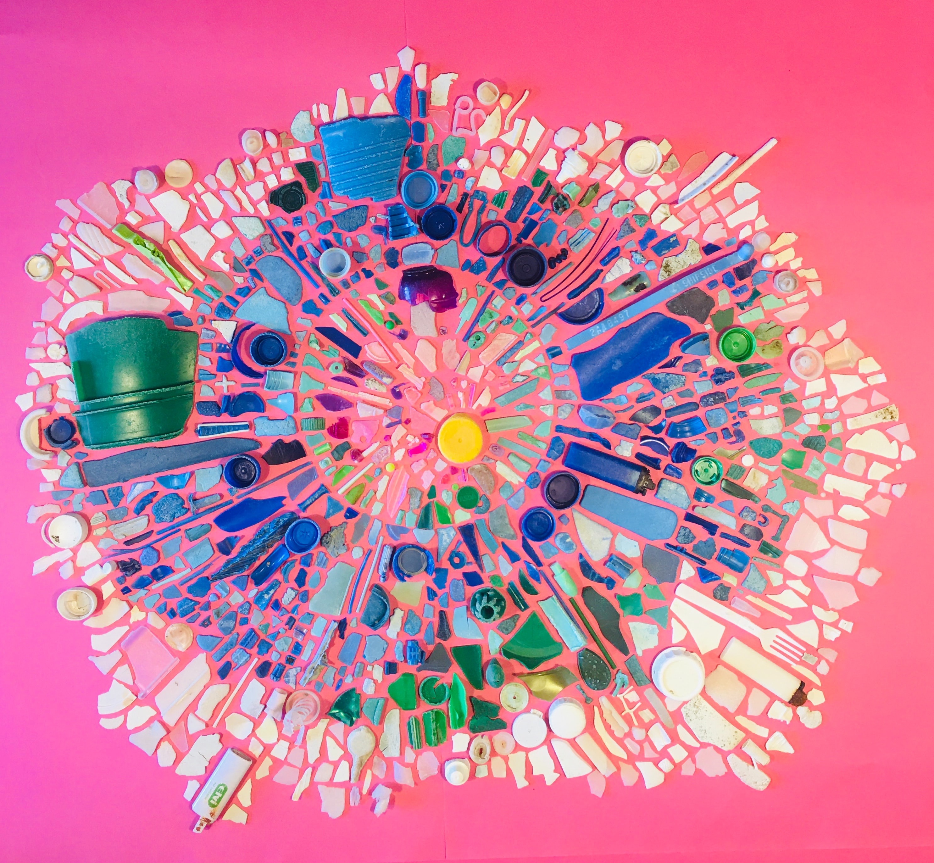 An assemblage of plastic on a pink background creates an artful mosaic. 