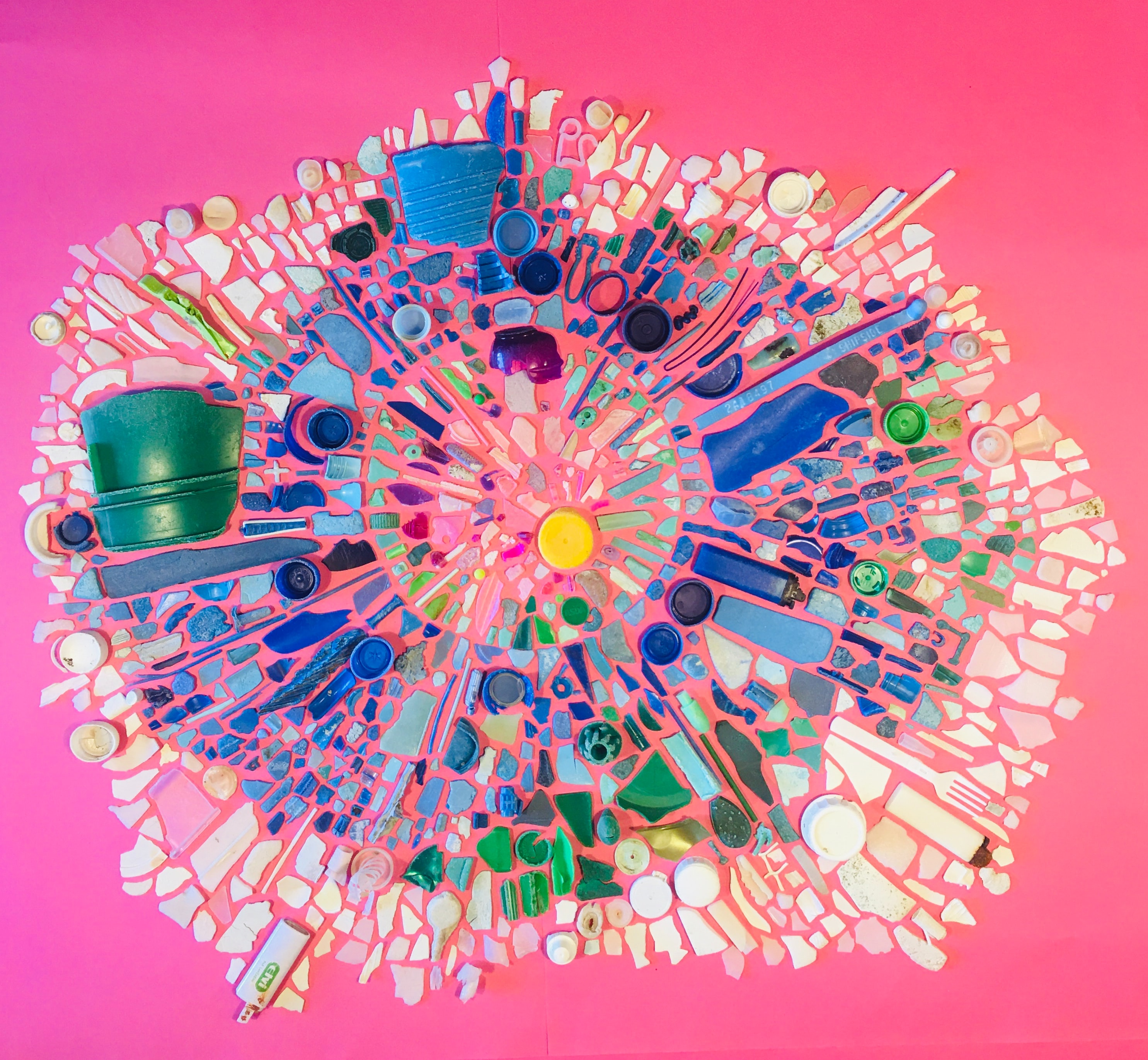 An assemblage of plastic on a pink background creates an artful mosaic.