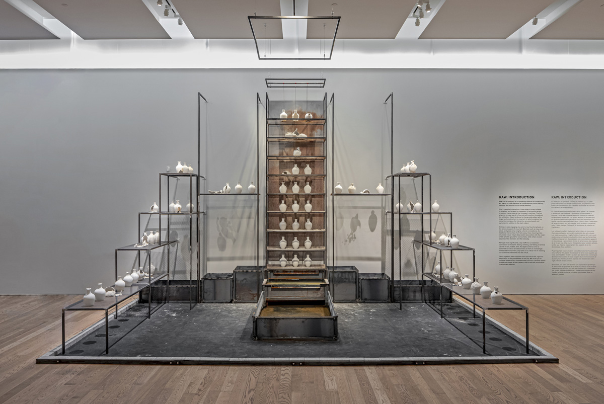 A cubic steel structure with white clay vessels on its shelves.