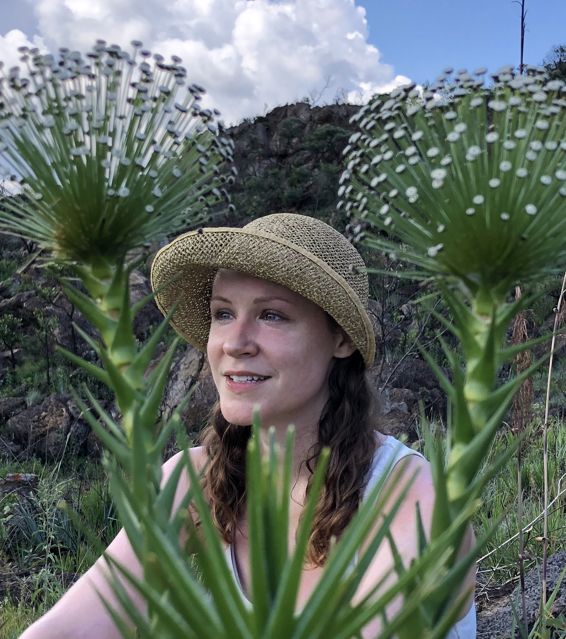 Image of a woman with twin tail brown hair smiling while sitting nature