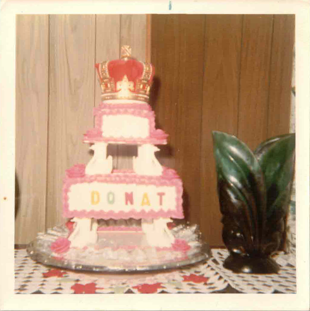 White cake with DONAT written on it and a red crown on top