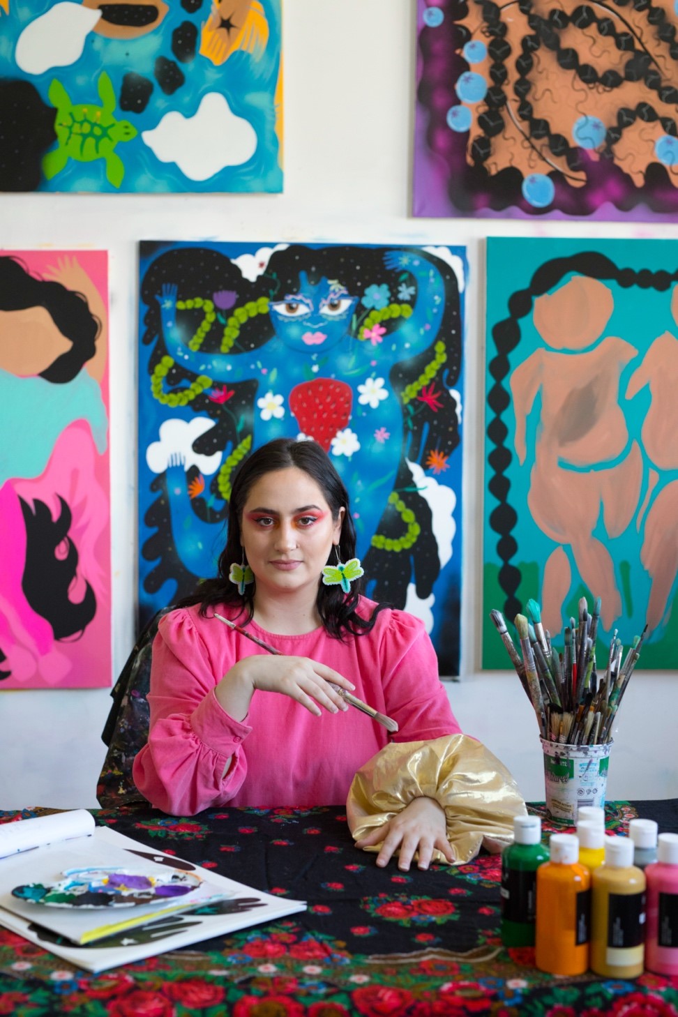 A person posing and surrounded by artwork