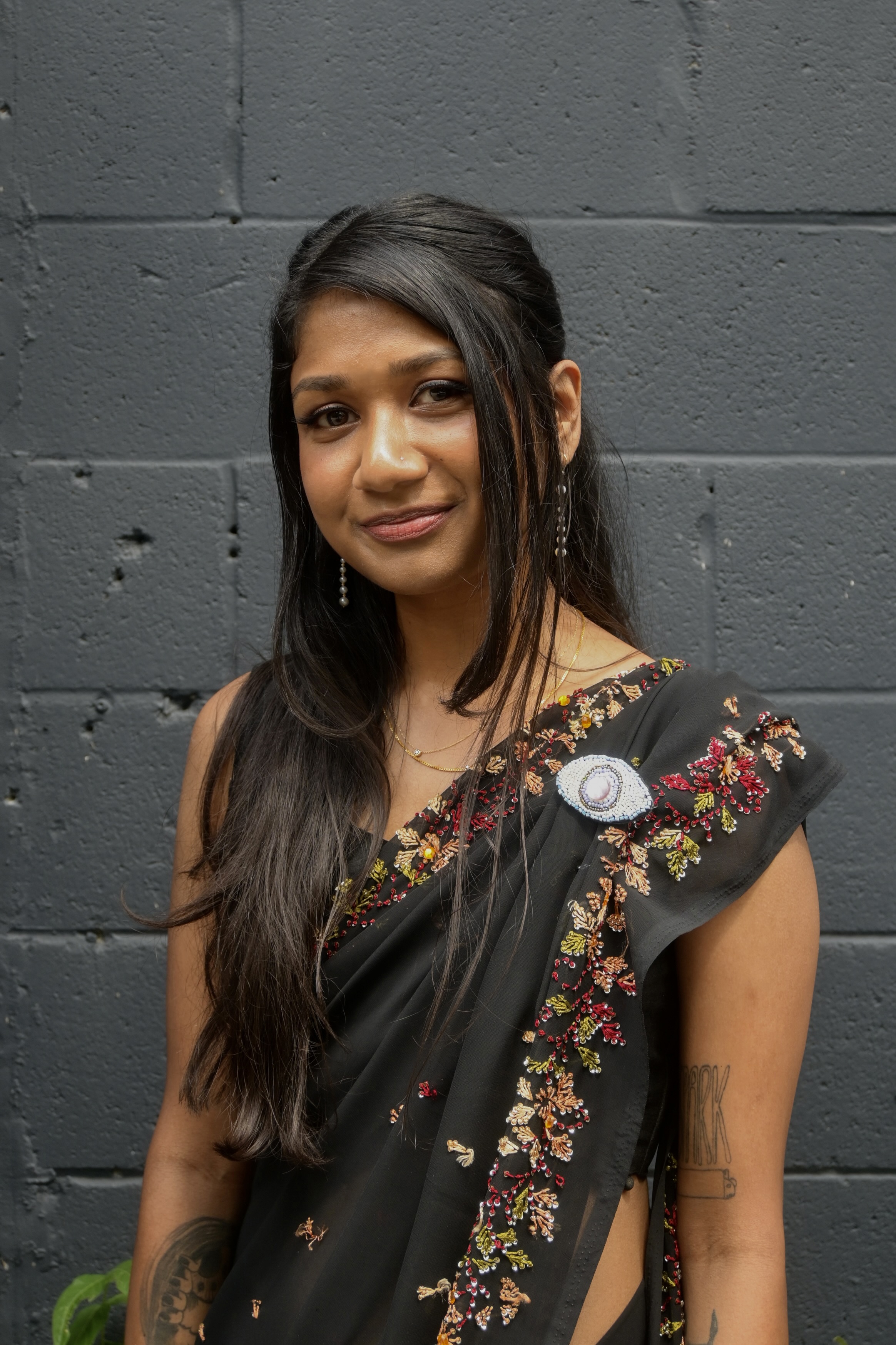 a woman with long black hair wearing a dark color sari.