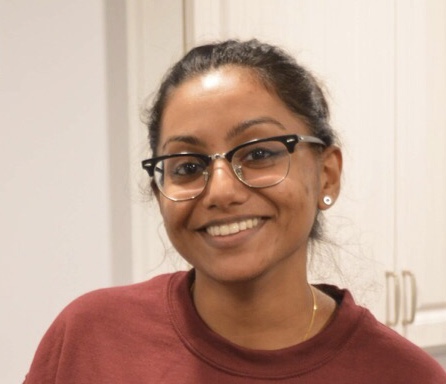 A person with glasses wearing a burgundy sweatshirt.