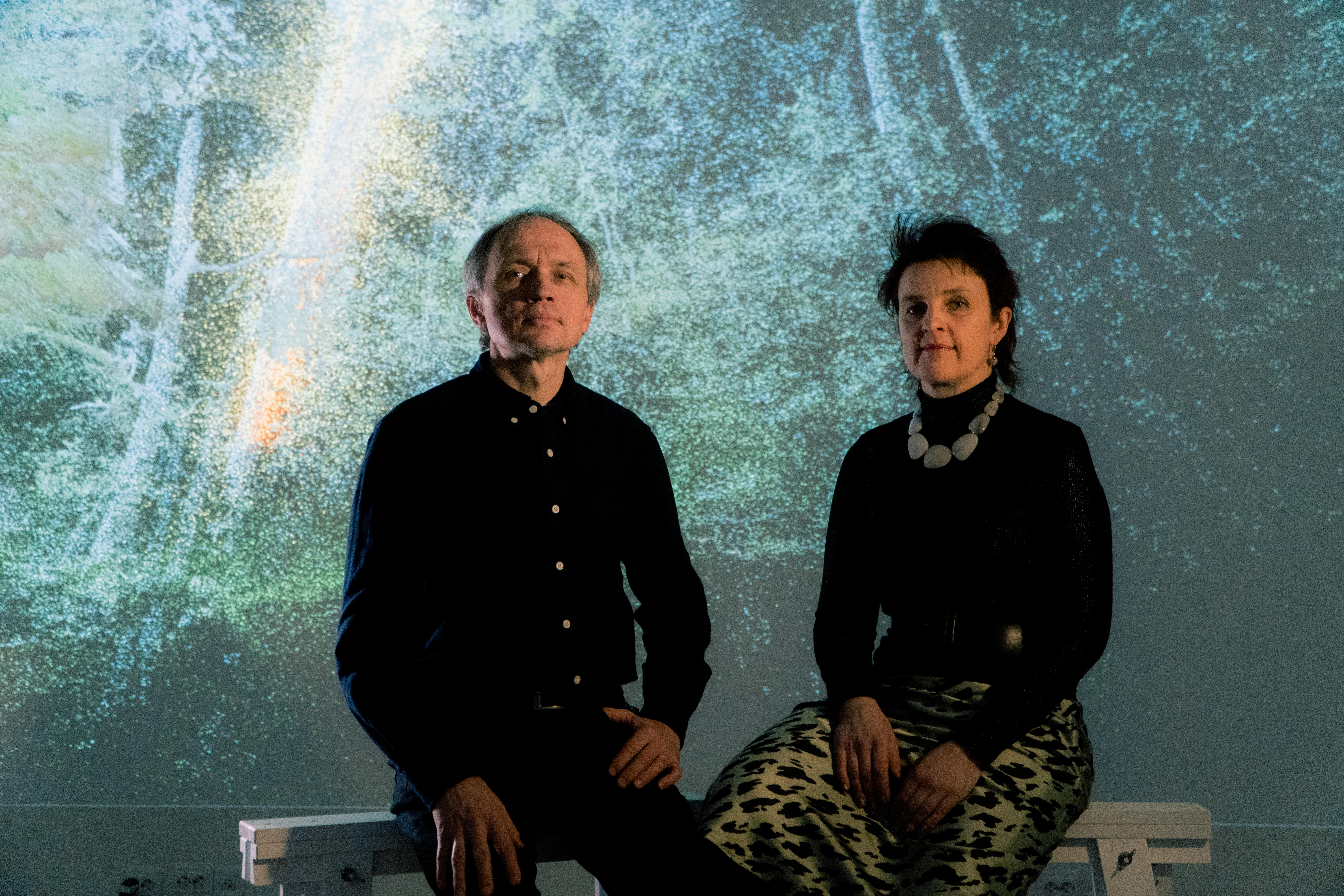 image of a man and a woman sitting while looking at a camera.