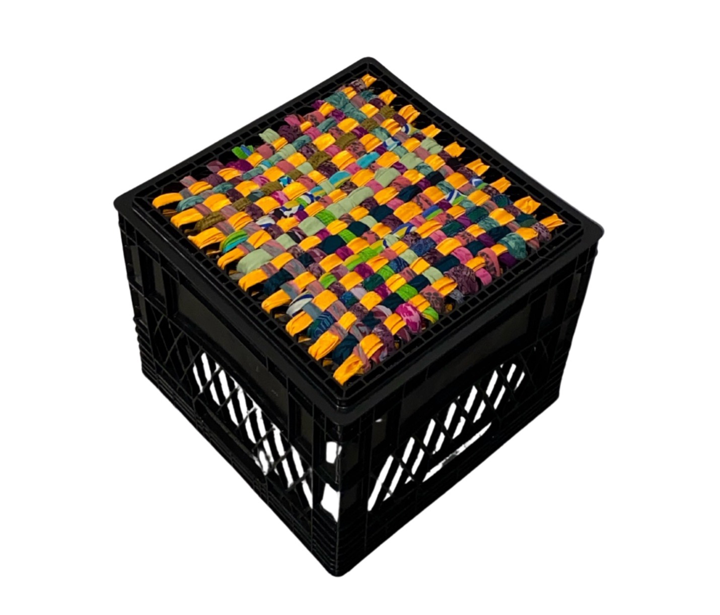 Photo of a colourful, weaved fabric atop a black milk crate.