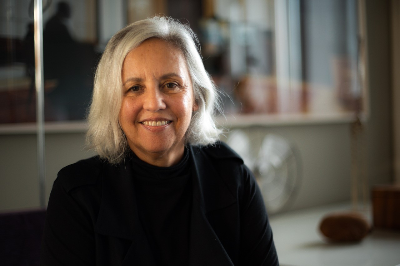 an image of woman with grey hair wearing black top smiling at the camera.