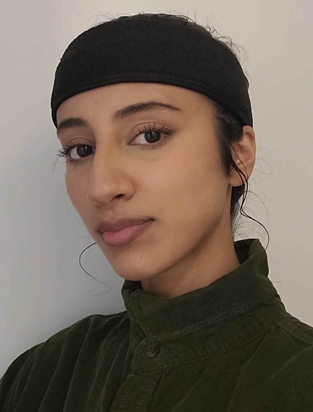 a woman wearing black hair covering with black turtle neck shirt.