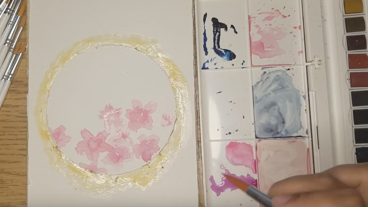 A photo of a hand mixing water colour paints.