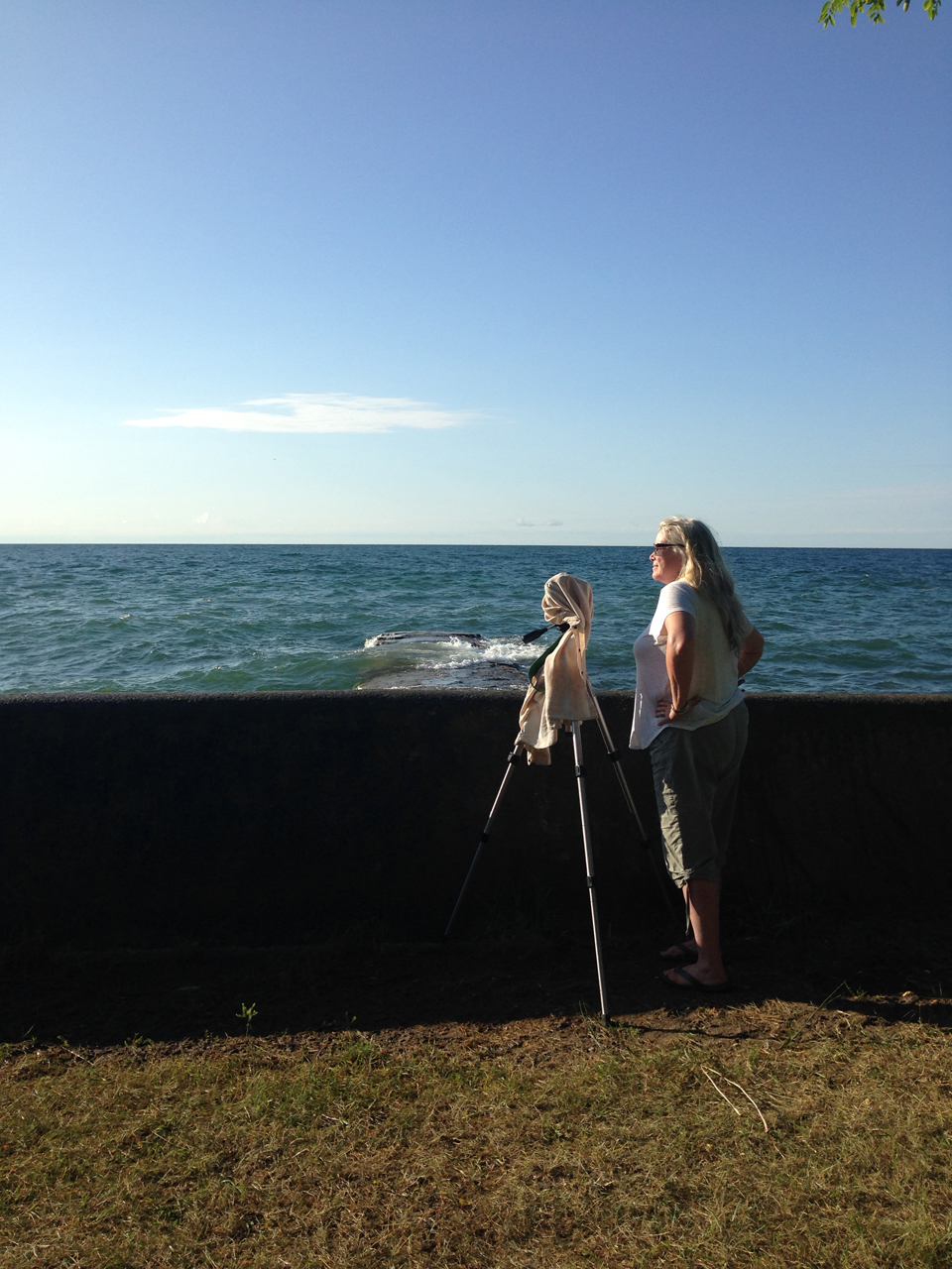 photo of the artist and her camera looking out over water