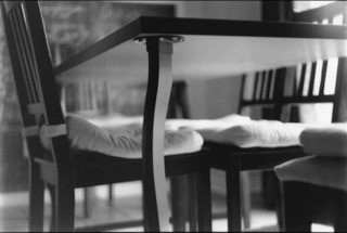 black and whit photo of underside of table with chairs