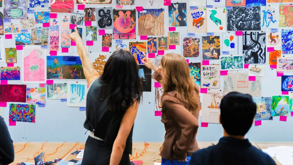 People looking at a wall filled with artwork for sale