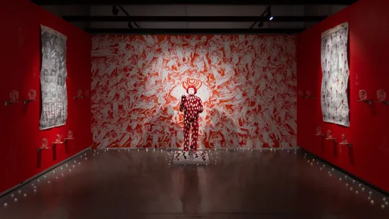 Installation view of Doktor Karayom: No One’s At Home (Walang Tao Sa Bahay). Red and white sculpture, in front of red and white wall mural.