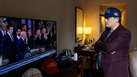 Man watches television coverage of U.S. President Donald Trump’s inauguration while wearing a dark blue hat with a Canadian flag on the side. 