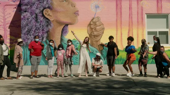 Group of people posing in front of a mural.