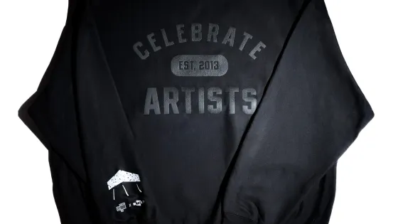 Black sweatshirt with white letters: Celebrate Artists and the OCADU logo is on the sleeve.