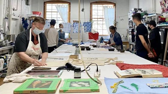 A group of people working around a table in the Contemporary Textile Studio.