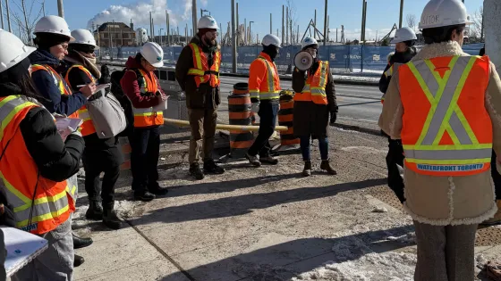 People in neon vests and construction hats standing outside