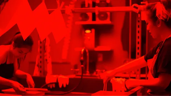 Two people working in a photography dark room and printing photos.