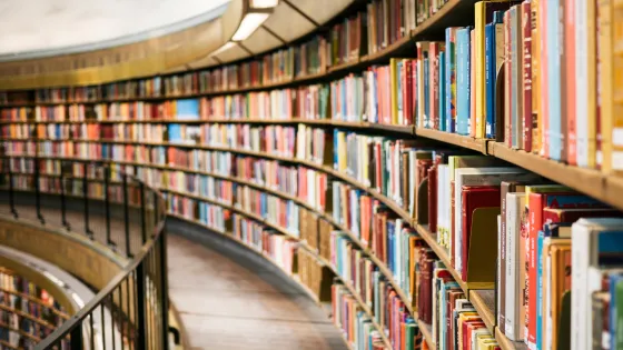 color photo of a curved library wall, filled end to end with books.