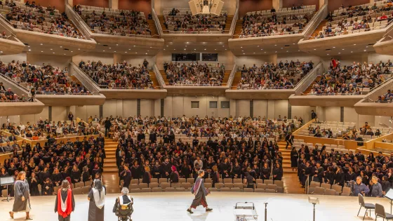 Convocation stage looking out onto crowd. Student crossing across the stage. 