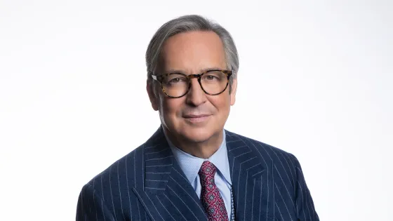 Colour photo of Chancellor Jaime Watt wearing a pin-striped navy suit and red patterned tie. 