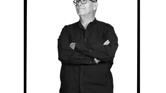 A man standing with arms crossed wearing eye glasses