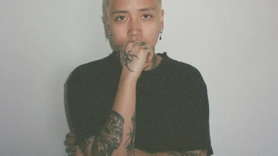 A woman wearing a black t-shirt with short blonde hair. 