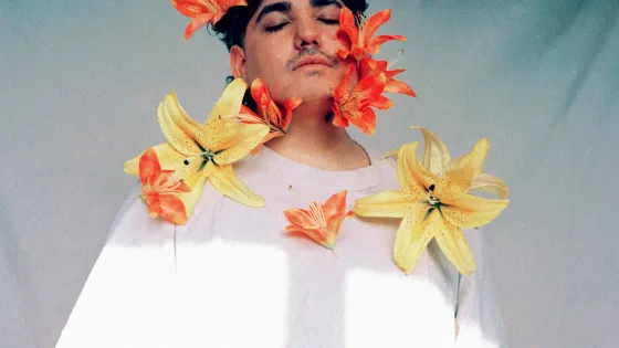 A man with black short hair wearing a white t-shirt with yellow and orange lilies on them