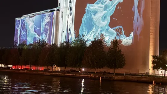 A photo of the Canada Malting Silos with a large-scale projection mapping that looks like water cascading down the building.