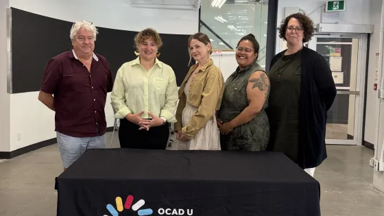 Image (left to right): Dr. David Griffin, Jennie Suddick, Meichen Waxer, Danielle Nadine Pierre and Deanne Fisher standing behind a table with a black tablecloth. The logo on the tablecloth says, "OCAD U International Programs & Collaborations Office."