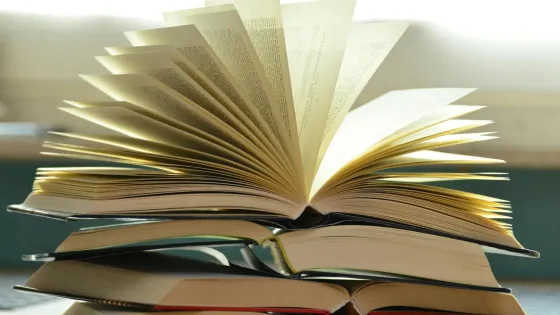 A pile of paper books with one book open pages