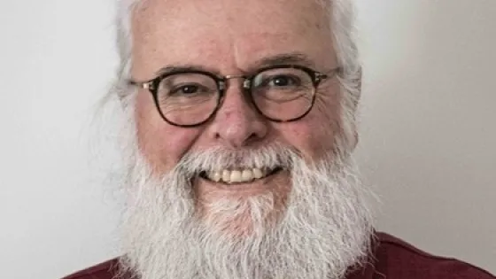 Photo of man with white hair and white beard wearing glasses