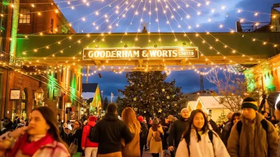 Distillery District during the holiday season. Festive lights hand overtop of a large crowd.