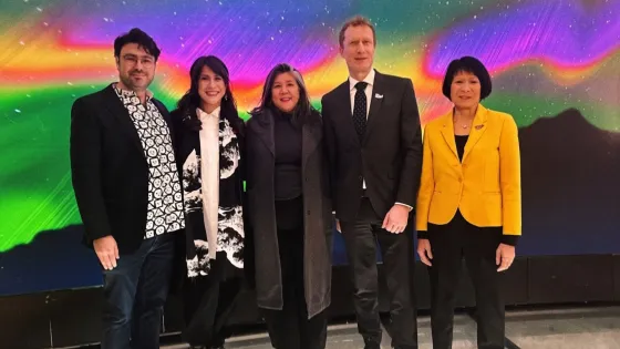 Five people standing in front of a colourful background